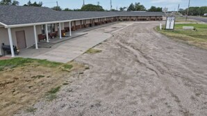 Un motel con zona de estacionamiento techada y un cartel que indica 'West Lake Inn'.