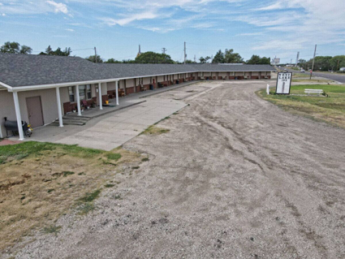 A motel with a covered parking area and a gravel driveway.