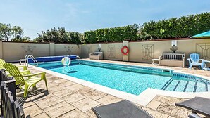 En swimmingpool med liggestole og en redningskrans på væggen.