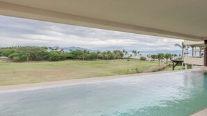 Zona de piscina con vista a un paisaje cubierto de césped y montañas a lo lejos.