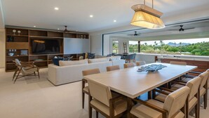 Una sala moderna con televisor grande, sofá y comedor.