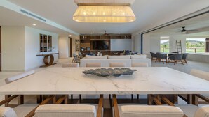 Amplia sala de estar con una gran mesa de mármol, asientos cómodos, televisor y un balcón con vistas.