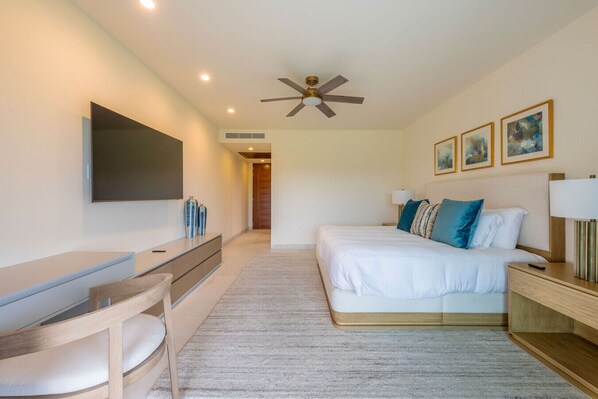 Una habitación de hotel moderna con cama, mesita de noche, lámpara, televisor y ventilador de techo.