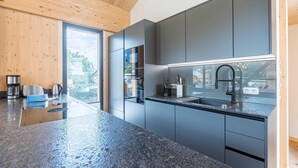 A modern kitchen with grey cabinets, a granite countertop, and a window overlooking a residential area. - Stylish Penthouse With Sauna (Sankt Georgen am Kreischberg)