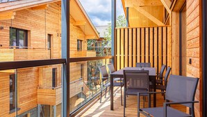 A modern wooden cabin with a balcony, large windows, and a dining area with chairs and a table. - Stylish Penthouse With Sauna (Sankt Georgen am Kreischberg)