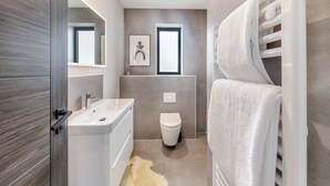 Un baño moderno con lavamanos, inodoro y toallero blancos.