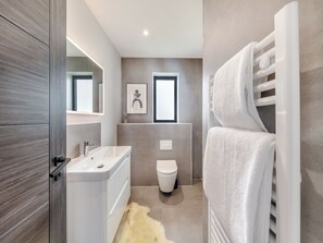 Un baño moderno con lavamanos, inodoro y toallero blancos.