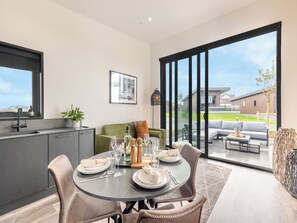 A modern kitchen with a dining area, large sliding glass doors to a patio, and a view of a residential area.