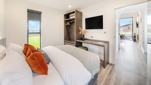 Un dormitorio moderno con cama, escritorio y televisor.