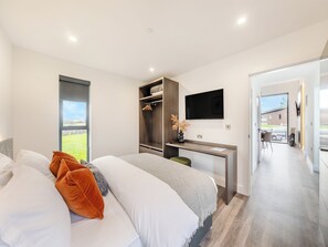 Un dormitorio moderno con cama, escritorio y televisor.