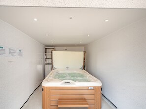 Una habitación moderna con una cama de madera, techo blanco y un estante con objetos.