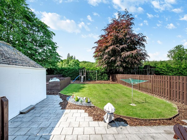 A backyard with a play area, a covered picnic table, and a wooden fence.