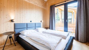 A modern bedroom with a large bed, wooden walls, and a view of the outside.