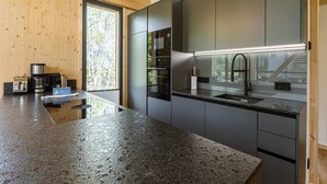 A modern kitchen with dark cabinets, a granite countertop, and a large window providing natural light.