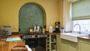 A kitchen with a tiled backsplash, a stove, a sink, and various kitchen appliances. - 2 bedroom accommodation in Hovingham, near Helmsley (Hovingham, near Helmsley)