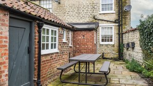 A stone house with a tiled roof, a brick door, and a picnic table in the yard. - 2 bedroom accommodation in Hovingham, near Helmsley (Hovingham, near Helmsley)