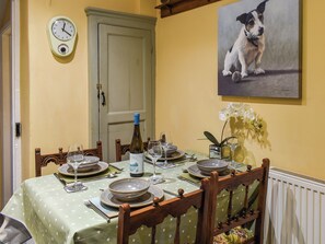 Une table à manger dressée avec des assiettes, des verres et une bouteille, entourée de chaises.