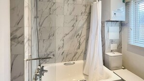 Un baño con bañera, ducha e inodoro.