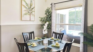 A dining area with a glass table, black chairs, and a vase of white flowers. - 4 Bedroom villa - private pool & game room near Disney (Kissimmee)