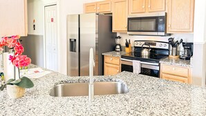 A modern kitchen with granite countertops, stainless steel appliances, wooden cabinets, and a built-in microwave. - 4 Bedroom villa - private pool & game room near Disney (Kissimmee)