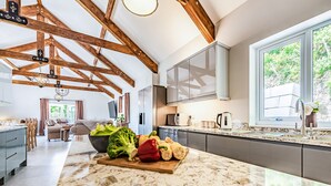 A spacious kitchen with a marble countertop, wooden beams, and a large window. - 5 bedroom accommodation in Llansawel, near Llandeilo (Llansawel, near Llandeilo)