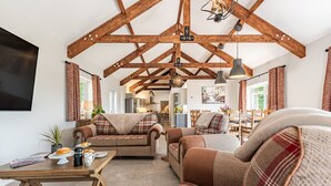 A spacious living area with a high ceiling, wooden beams, a dining table, and a sofa set. - 5 bedroom accommodation in Llansawel, near Llandeilo (Llansawel, near Llandeilo)
