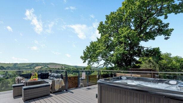 A deck with outdoor seating, a hot tub, and a view of the countryside. - 5 bedroom accommodation in Llansawel, near Llandeilo (Llansawel, near Llandeilo)