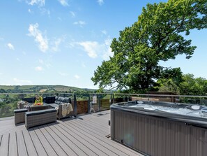 A deck with outdoor seating, a hot tub, and a view of the countryside.