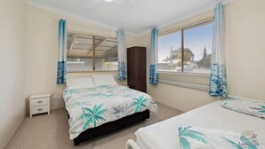 A bedroom with two beds, a wardrobe, and a window with curtains. - Aqua Sands Chalets-Nestled in the heart of Lancelin (Lancelin)