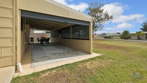 Eine Garage mit Tisch und Stühlen, einem überdachten Bereich und blauem Himmel.