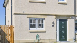 A two-story building with a beige exterior, a green door, and a visible number '5' on the wall. - 3 bedroom accommodation in Inverness (Inverness)