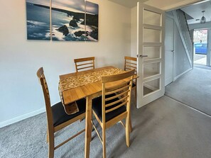 Ein Essbereich mit Tisch und Stühlen, ein Bild an der Wand und eine Tür zu einer Treppe.