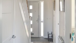 A hallway with a staircase, a door, a radiator, and a small table. - 3 bedroom accommodation in Inverness (Inverness)