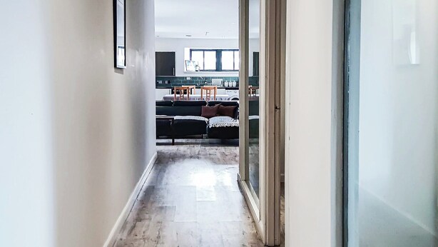 A narrow hallway leading to a kitchen area with a dining table and chairs. - The Old Mill Apartment - UK48028 (Tain)