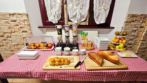 A breakfast buffet table with croissants, bread, fruits, and beverages. - Francy (Ponte Capriasca)