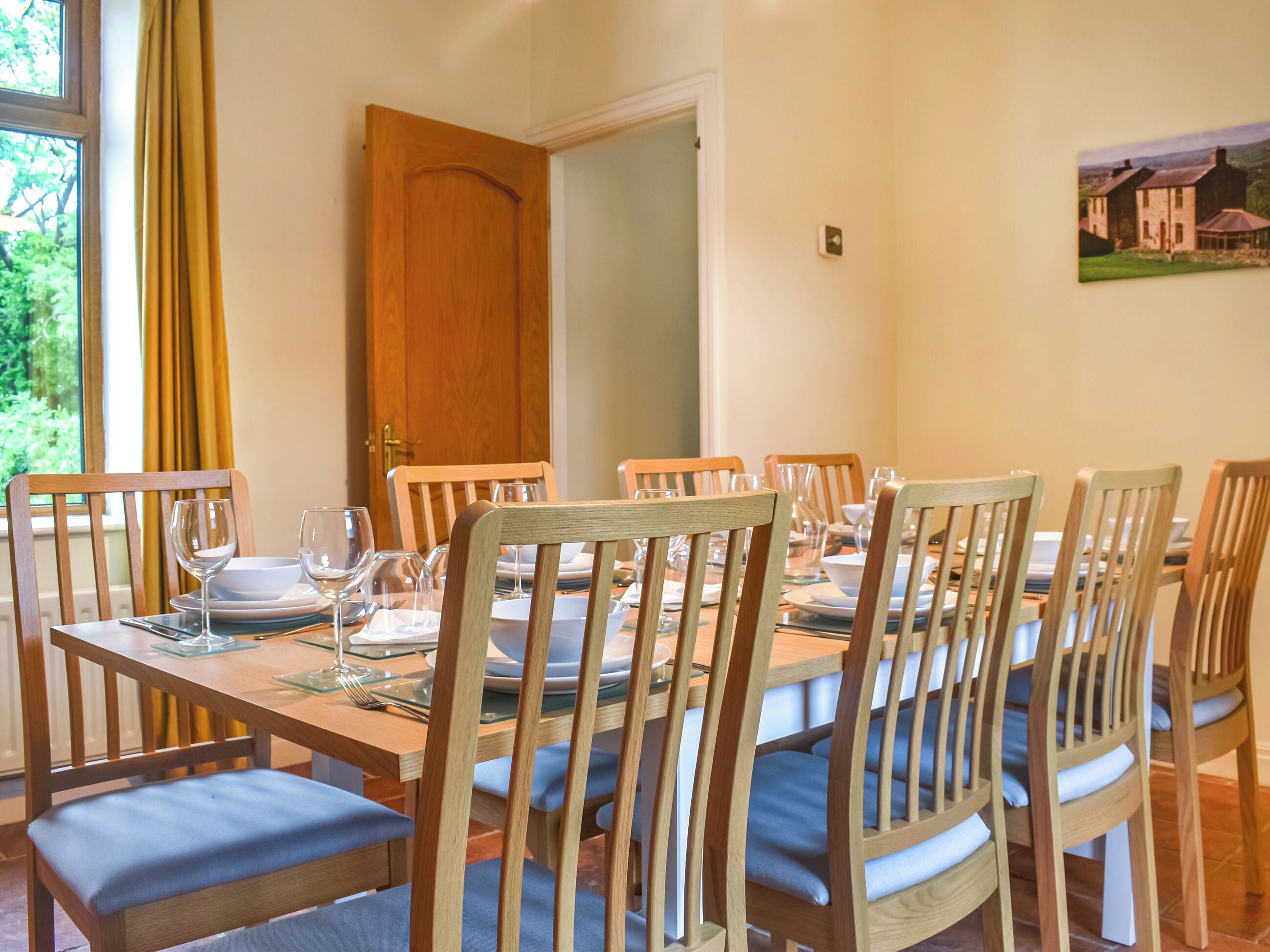Un comedor con sillas y mesas de madera, una puerta y un cuadro en la pared.