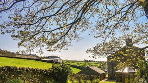 A stone wall, a grassy area, and a building with a glass door. - 4 bedroom accommodation in Hainworth, near Keighley (Hainworth, near Keighley)
