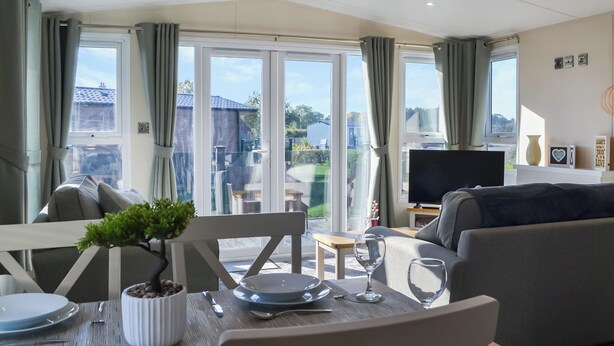 A living room with a dining table, chairs, a sofa, a TV, and a view of the outside. - 2 bedroom accommodation in Carnaby, near Bridlington (Carnaby, near Bridlington)