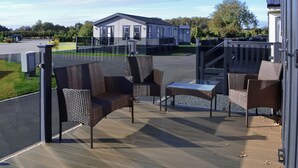 A covered outdoor seating area with wicker furniture and a view of a residential building in the background. - 2 bedroom accommodation in Carnaby, near Bridlington (Carnaby, near Bridlington)
