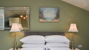 Un lit bien fait, avec du linge de lit blanc et deux serviettes pliées au centre.