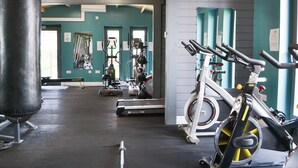 Une salle de sport équipée de matériel d’exercice, d’un sac de frappe et d’un tapis de course.