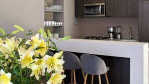 A modern kitchen with a central island, bar stools, a coffee machine, and a ceiling fan. - CASA XANTHE (San Miguel de Allende)