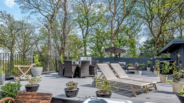 Une terrasse sur le toit, dotée de chaises longues, d’un jacuzzi et de plantes en pot.