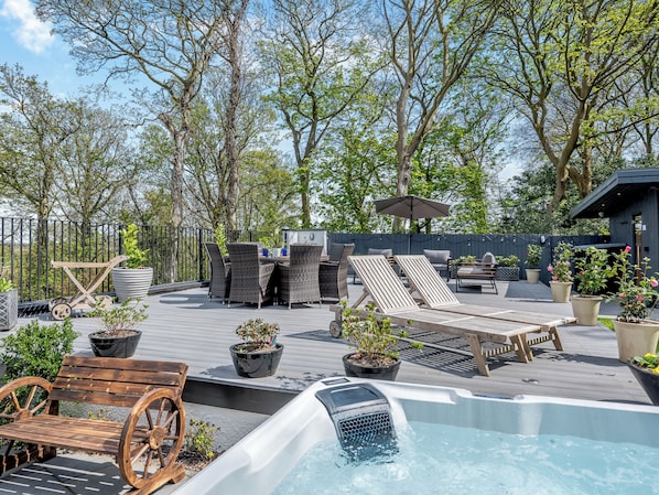 A rooftop patio with lounge chairs, a hot tub, and potted plants.