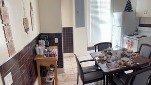 A kitchen with a dining table set for four, a coffee machine, and a small refrigerator.