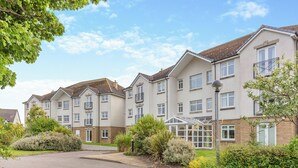 A multi-story residential building with a central courtyard, balconies, and a well-maintained garden. - No.4 The Links Apartments (Brora)