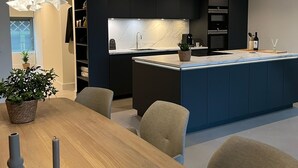 A modern kitchen with dark cabinetry, a marble countertop, and a central island. - Copenhagen Residence | Holiday home with Scandinavian flair | View of the water. (Harderwijk)