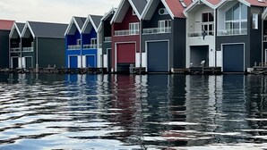 A row of waterfront houses with gabled roofs and large garage doors. - Copenhagen Residence | Holiday home with Scandinavian flair | View of the water. (Harderwijk)
