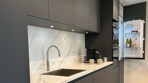 A modern kitchen with dark cabinetry, a marble countertop, and a built-in sink. - Copenhagen Residence | Holiday home with Scandinavian flair | View of the water. (Harderwijk)