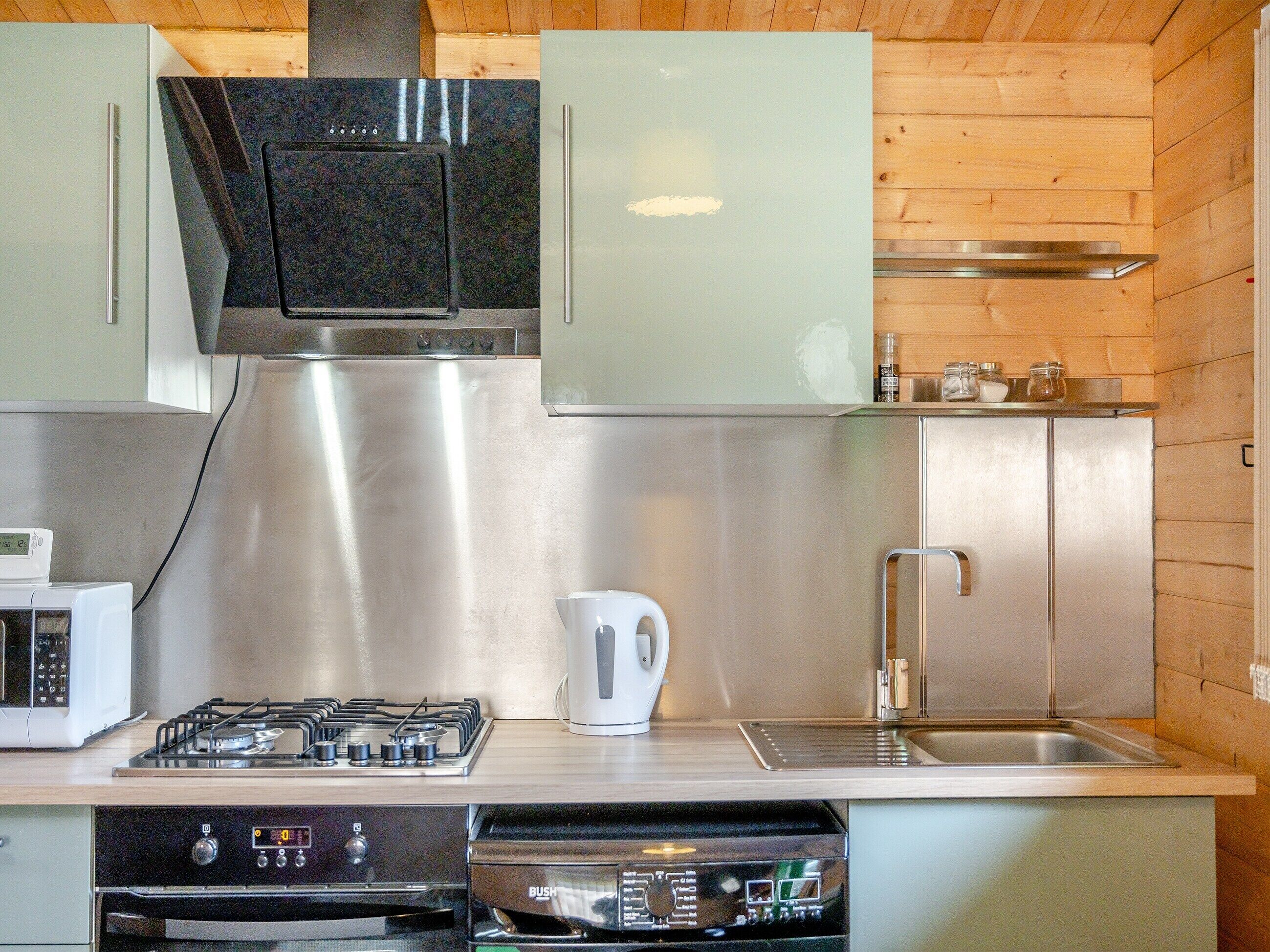 A modern kitchen with stainless steel appliances, wooden paneling, and a built-in dishwasher.